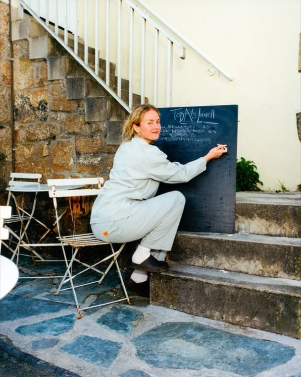 A team member writing today's menu on the chalkboard outside the venue.